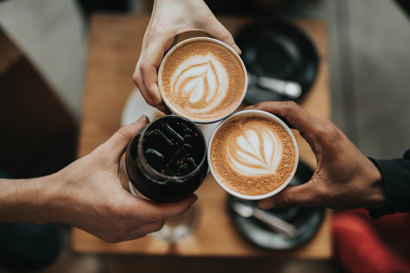 Two hands meeting over cups of coffee